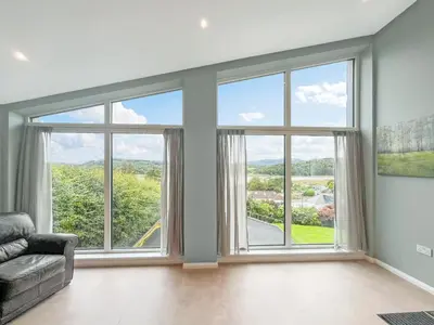 a living room with large windows and a couch at Grey Rocks Apartment in Kippford