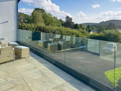 a balcony with glass railing on a house at Grey Rocks Apartment in Kippford