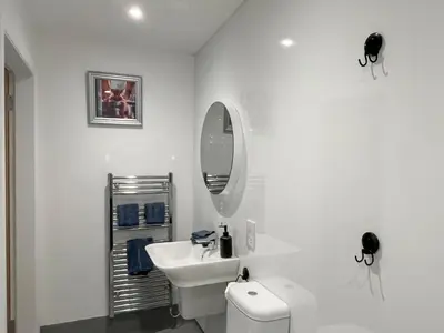 a white bathroom with a sink and a mirror at Grey Rocks Apartment in Kippford