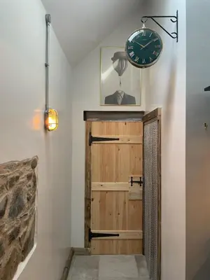 a clock on the wall above a door in a room at Pink Cottage in Kirkcowan