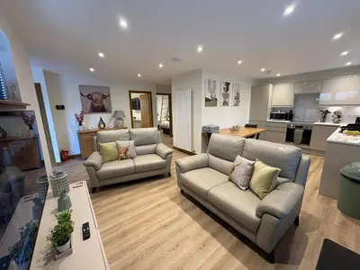 a living room with two couches and a kitchen at Woodway Lodge in Dumfries