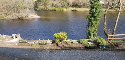 a park with a bench next to a river at Riverside Cottage in Minnigaff