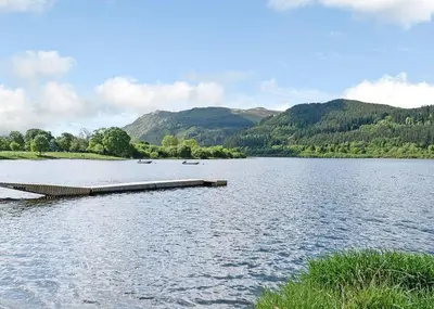 a dock on a lake with mountains in the background at Bassenthwaite Lakeside Lodges in Bassenthwaite
