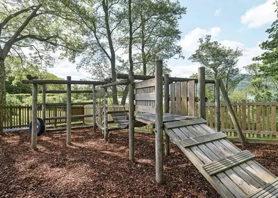 a playground with two wooden benches in front of a fence at Bassenthwaite Lakeside Lodges in Bassenthwaite