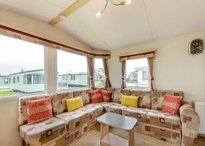 a living room with a couch with colorful pillows at Rowanbank Caravan Park in Beckfoot