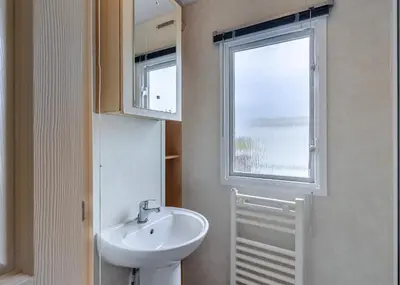 a bathroom with a sink and a window at Rowanbank Caravan Park in Beckfoot