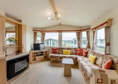 a living room with a couch and a tv at Rowanbank Caravan Park in Beckfoot