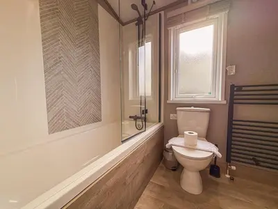 a bathroom with a toilet and a shower and a window at Hornbeam Lodge in Bassenthwaite