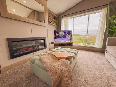 a living room with a couch and a tv at Hornbeam Lodge in Bassenthwaite