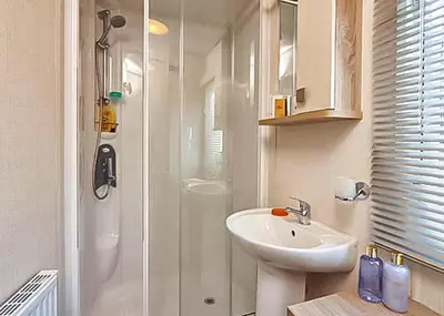 a white bathroom with a sink and a shower at Stanwix Park in Silloth