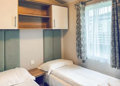 two beds in a small room with a window at Whitecairn Holiday Park in Glenluce