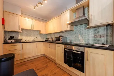 a kitchen with wooden cabinets and black counter tops at North Loft a Modern Apartment in Cockermouth in Cockermouth