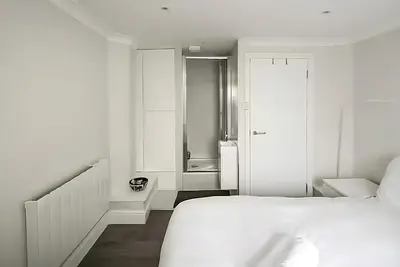 a white room with a bed and a bathroom at 1 Bed Flat in Shoreditch near Station by Hostroo in Moffat