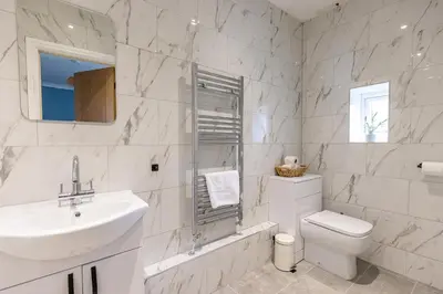 a white bathroom with a sink and a toilet at EASTCOTE FARM - Spacious 5-Bed Home with Views, Garden & Playroom in Silloth