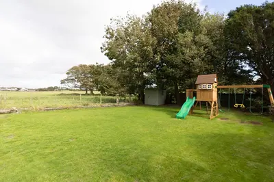 a playground with a slide and a house at EASTCOTE FARM - Spacious 5-Bed Home with Views, Garden & Playroom in Silloth