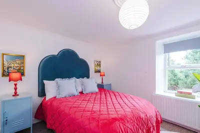 a bedroom with a red bed with a blue headboard at Springholm Cottage Family Retreat - Sleeps 10 in Bootle