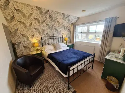 a bedroom with a bed and a chair at Lane Head Farm Country Guest House in Troutbeck