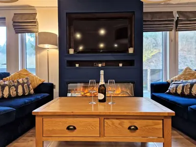 a living room with a wine bottle and two glasses on a coffee table at High Spy Luxury Lodge in Keswick