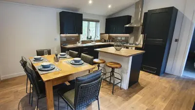 a kitchen with a wooden table and a kitchen with black cabinets at High Spy Luxury Lodge in Keswick
