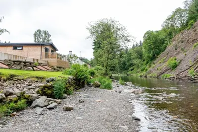 a house next to a river with a building at High Spy Luxury Lodge in Keswick