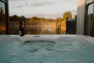 a hot tub with two glasses and a bottle of wine at Landal Ullswater Heights in Great Blencow