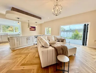a living room with a couch and a kitchen at Jaytrees, Keswick - Luxury bungalow with hot tub in Keswick