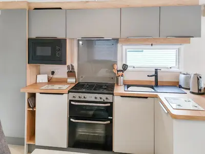 a small kitchen with a stove and a microwave at Melfell View - Uk50086 in Penruddock