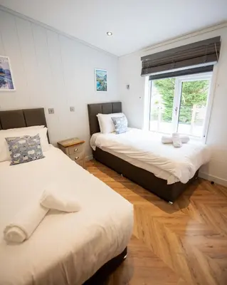 two beds in a room with a window at Great Gable Riverside Luxury Lodge in Keswick