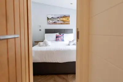 a bedroom with a bed with white sheets at Great Gable Riverside Luxury Lodge in Keswick