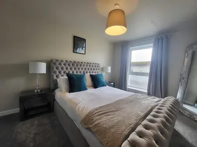 a bedroom with a large bed with blue pillows at The MacIntyre - Coorie Doon Stays in Kilmarnock