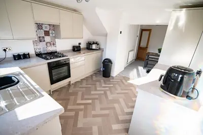 a kitchen with white cabinets and a stove top oven at Cottage in Seaton in Siddick