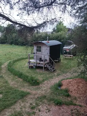 a small shed in a field with a table and a bench at Shepherd's Hut Harmony at A Therapeutic Space in Moniaive