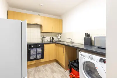 a kitchen with wooden cabinets and a washing machine at Lovely 2BED Whitehaven Apartment with Sea Views in Whitehaven