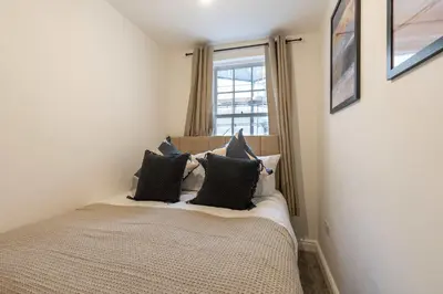 a bedroom with a bed with pillows and a window at Lovely 2BED Whitehaven Apartment with Sea Views in Whitehaven