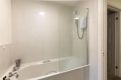 a bath tub with a glass shower in a bathroom at Lovely 2BED Whitehaven Apartment with Sea Views in Whitehaven