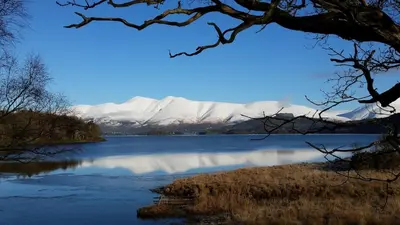 a view of a lake with snowy mountains in the background at Hot tub, Mountain View, 4-poster bed and log burner in Borrowdale Valley