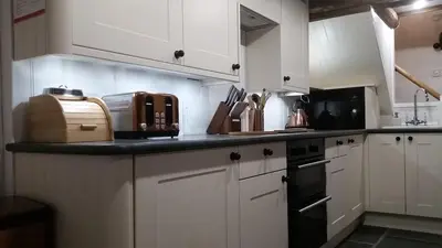 a kitchen with white cabinets and a black counter top at Hot tub, Mountain View, 4-poster bed and log burner in Borrowdale Valley