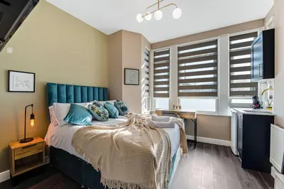 a bedroom with a bed with a blue headboard at Stylish Studio Retreat in Ideal Location in Moffat