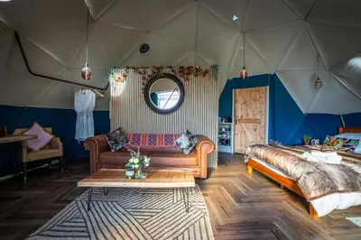 a room with a bed and a couch in a tent at Coorie Retreats Luxury Geo Domes and Cabins with Private Hot Tubs Cinema Firepit Spa and More in Portpatrick