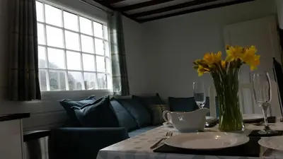 a living room with a table with a vase of yellow flowers at Mountain Lodge, Lake View, National Park in Borrowdale Valley