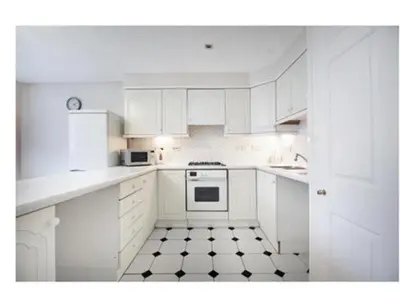 a kitchen with white cabinets and a black and white tile floor at 14 Maple Mews in Moffat