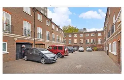 a parking lot with cars parked in front of brick buildings at 14 Maple Mews in Moffat