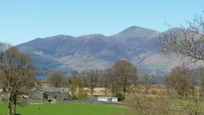 a view of a field with mountains in the background at 2 Double Bed Cottage Hottub Lake District Keswick in Keswick