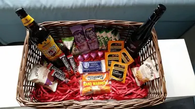 a basket filled with beer and snacks on a table at 2 Double Bed Cottage Hottub Lake District Keswick in Keswick