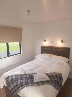 a bedroom with a bed with two towels on it at Amazing Sunsets and Sea Views - Lodge Cabin Farm Stay - Caol Ila - Lodge 8 in Stranraer