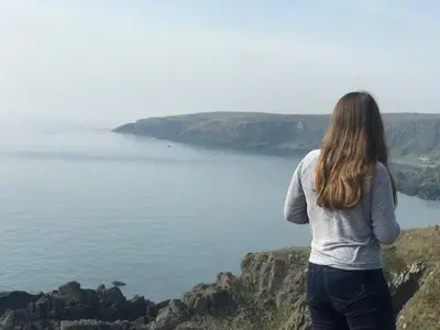 a woman standing on a cliff looking at the water at Amazing Sunsets and Sea Views - Lodge Cabin Farm Stay - Caol Ila - Lodge 8 in Stranraer