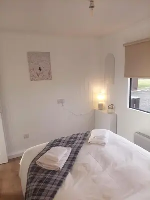 a white bedroom with a bed with two towels on it at Amazing Sunsets and Sea Views - Lodge Cabin Farm Stay - Caol Ila - Lodge 8 in Stranraer