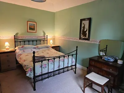 a bedroom with a bed and a dresser with two lamps at Morton Mains Cottage
