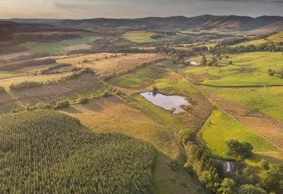 an aerial view of a field with a pond at Morton Mains Cottage