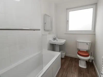 a white bathroom with a toilet and a sink at The Dairy in Newton Stewart